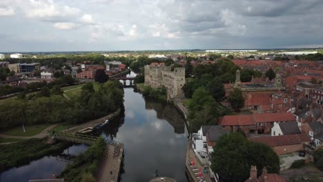 aerial drone footage starting behind a river boat in newark town lock that moving up and forward over to newark castle and gardens and panning down over the castle and gardens.