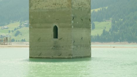 medium shot, scenic view of the window of kirchturm von altgraun in italy, people kite boarding in the background