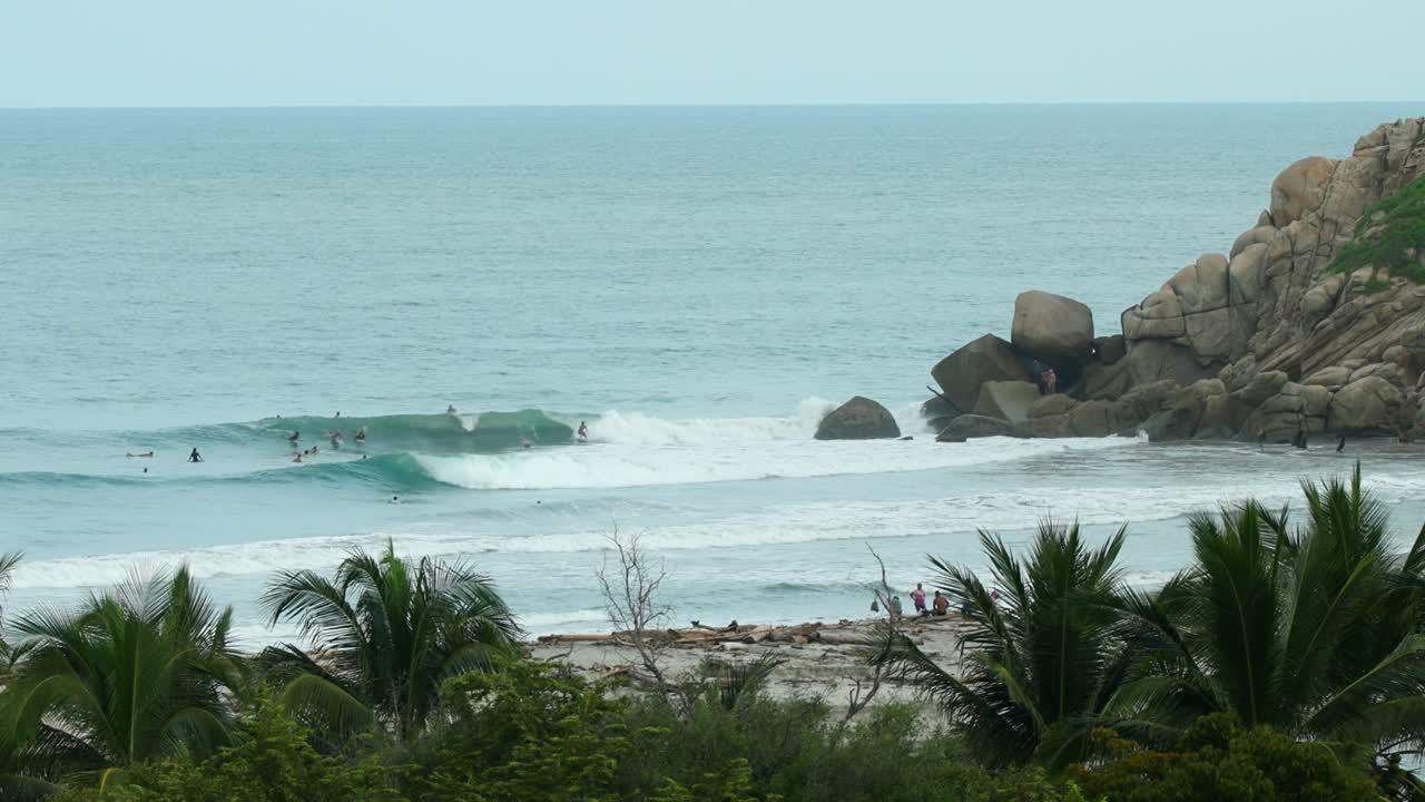 gente surfeando en aguas turquesas en una playa de méxico a la hora azul
