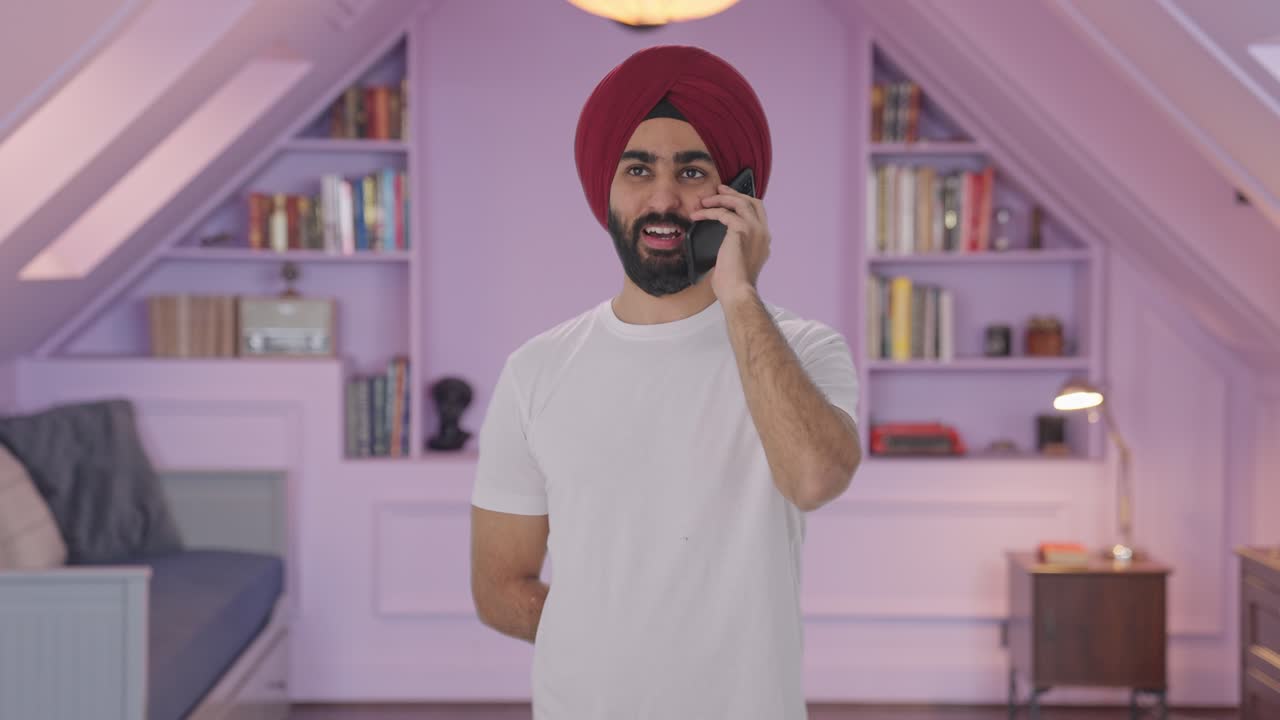 Uomo indiano Sikh felice che parla al telefono e sorride.