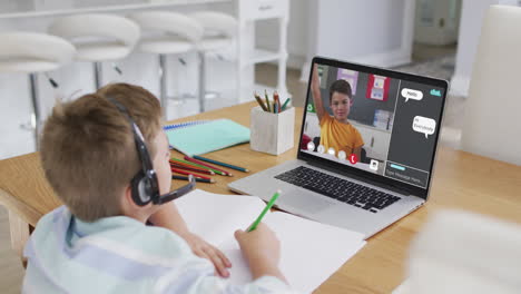 schoolboy using laptop for online lesson at home, with school friend and web chat on screen
