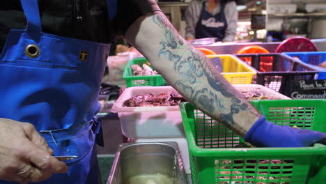 Oyster-farmer-opening-oyster-shells-in-a-fish-market-Sete-France-Herault