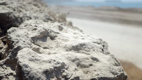 a still shot of a rock with 2 off-road vehicles passing each other in the background out of focus