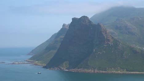 un barco navega a lo largo de los acantilados y montañas en la región del cabo de buena esperanza cerca de ciudad del cabo sudáfrica 1