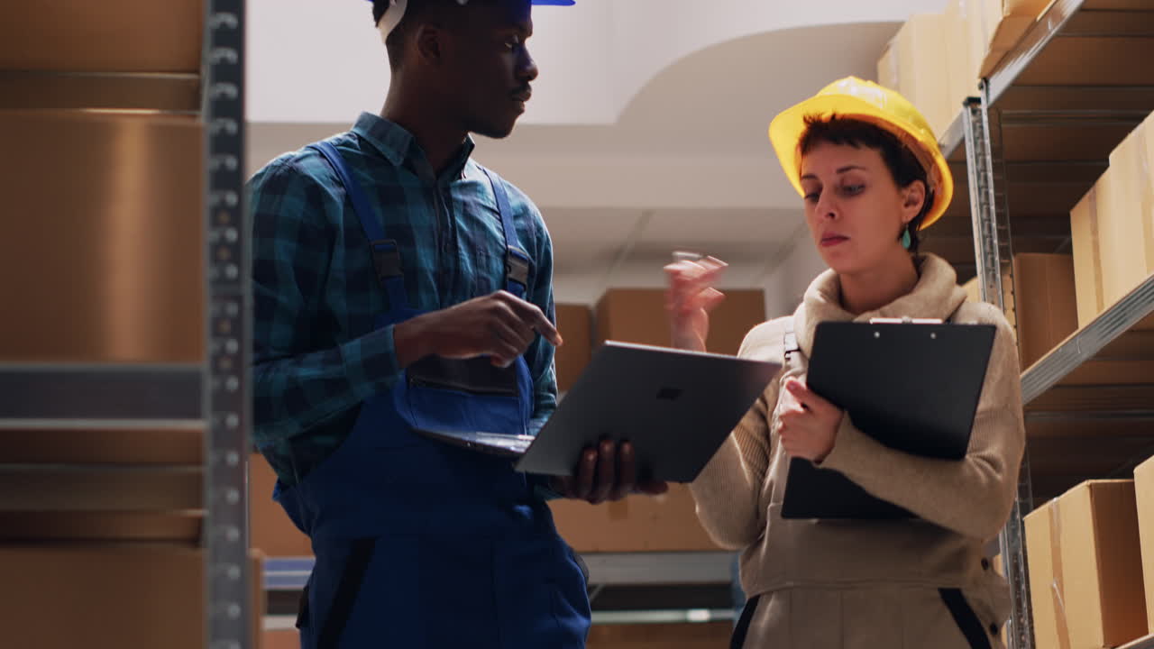 Warehouse workers checking inventory with a laptop and clipboard
