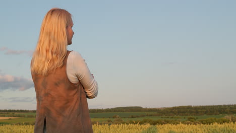 a farmer looks at a picturesque landscape with a field of wheat. view from the back