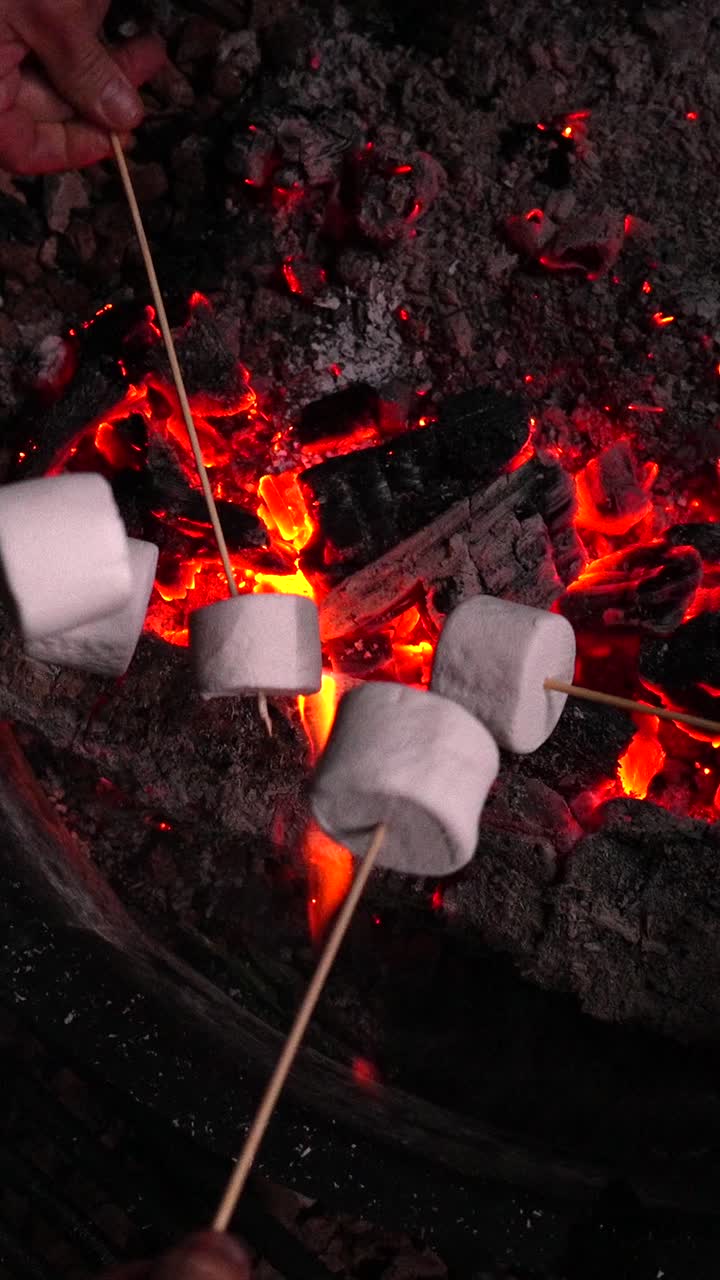 Arrostire marshmallow su braci ardenti di un falò di notte