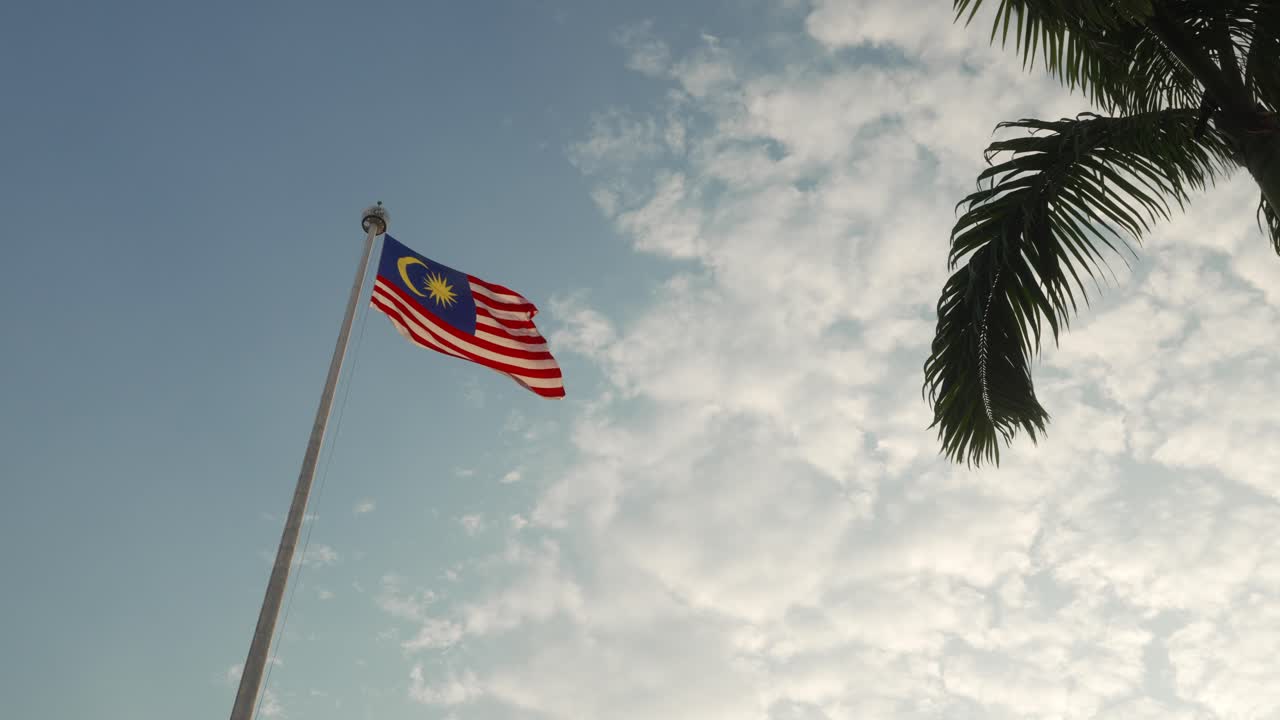 The Malaysian flag sways lightly in the wind on a clear day