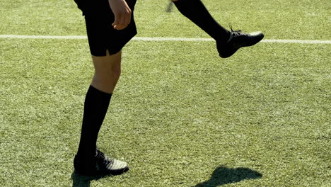 close up of an unrecognizable soccer player training freestyle tricks with the ball on a street football pitch on a sunny day