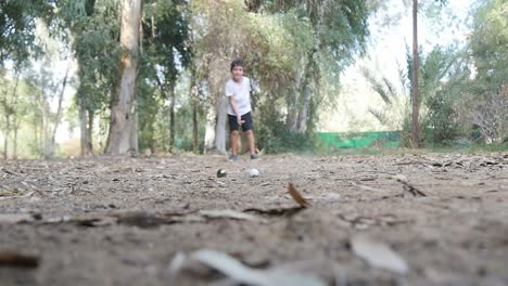 un niño jugando a las canicas en el parque lanza su canica hacia la cámara