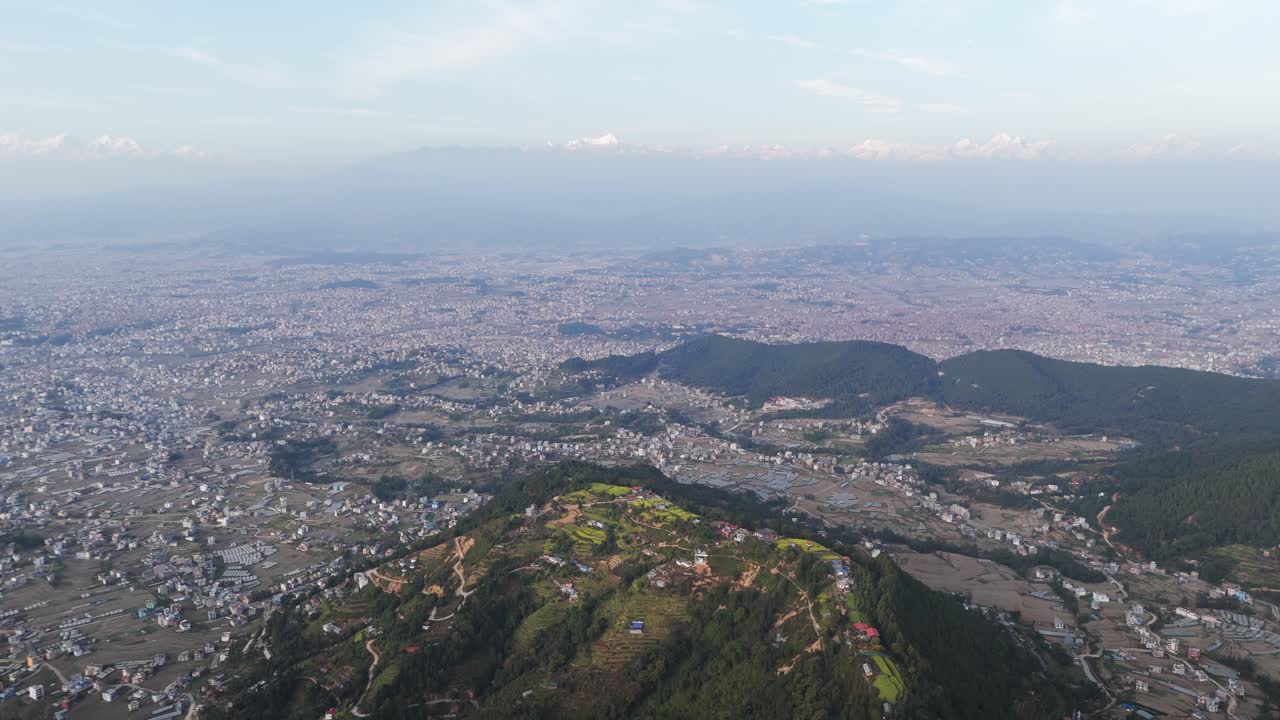A sweeping drone view of Kathmandu Valley reveals its dense urban layout, surrounding green hills, and distant Himalayan horizon, capturing the unique blend of culture, terrain, and city life in Nepal