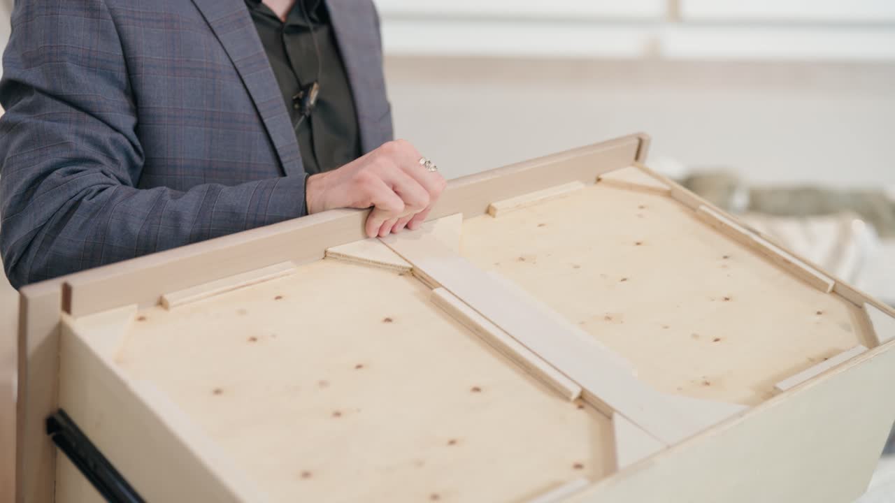 Suit-clad man showcases quality wooden drawer bottom in handheld store demo
