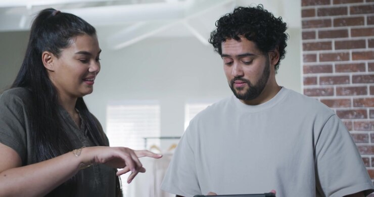 Two Colleagues Discussing Work on a Digital Tablet in a Studio