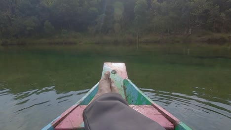 man relaxing at isolated traditional wood boat at river shore at day from flat angle