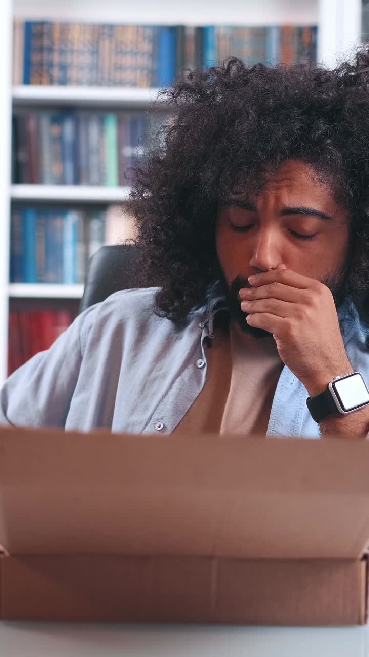 Excited man unboxing a surprise package at home on a sunny afternoon