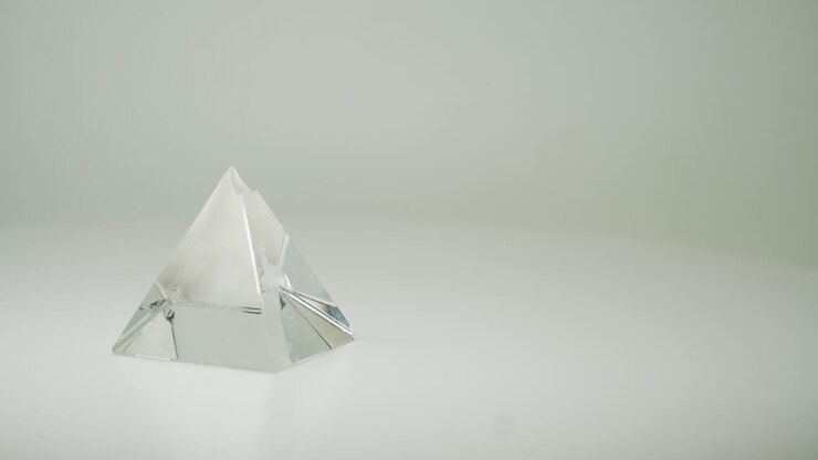 Costosa piramide di cristallo trasparente che ruota in senso orario con sfondo bianco puro - Primo piano