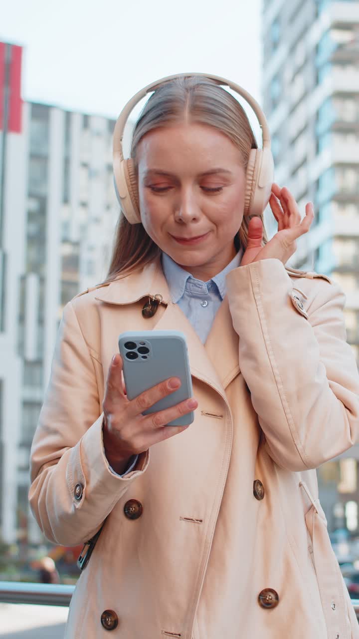 feliz mujer de negocios madura con auriculares inalámbricos bailando escuchando música en la calle del centro