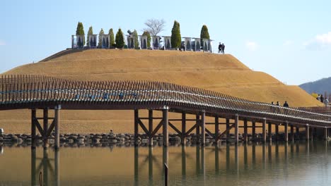 visitors walking along footbridge - bridge of dreams in lake garden of suncheonman bay national garden, suncheon city eco park, south korea