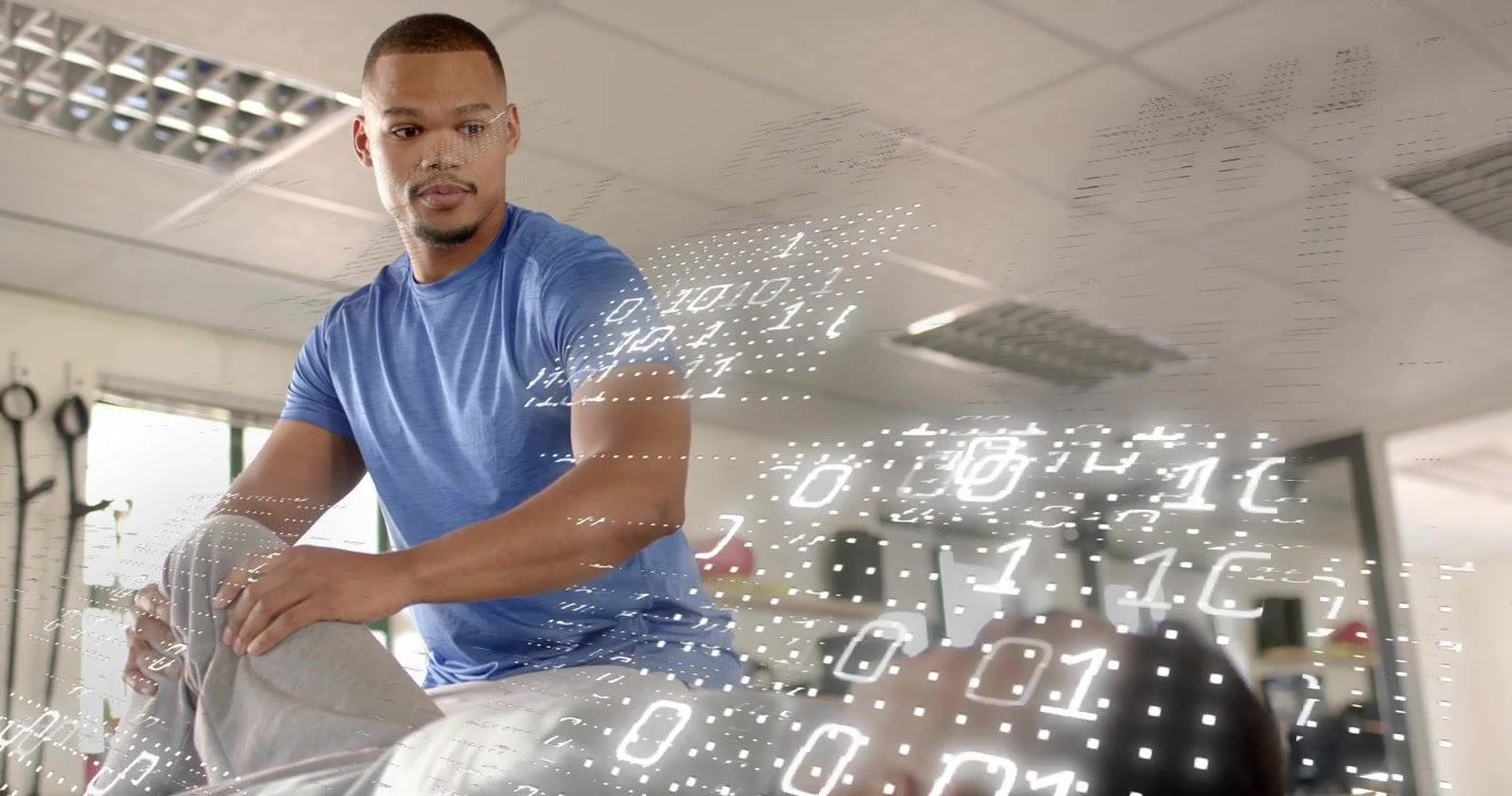 Trainer raising client leg in rehab studio while monitoring digital grid and binary overlay
