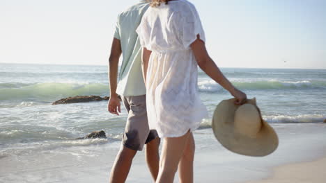 Una-Pareja-Birracial-Se-Encuentra-En-Una-Playa-De-Arena,-Frente-Al-Mar