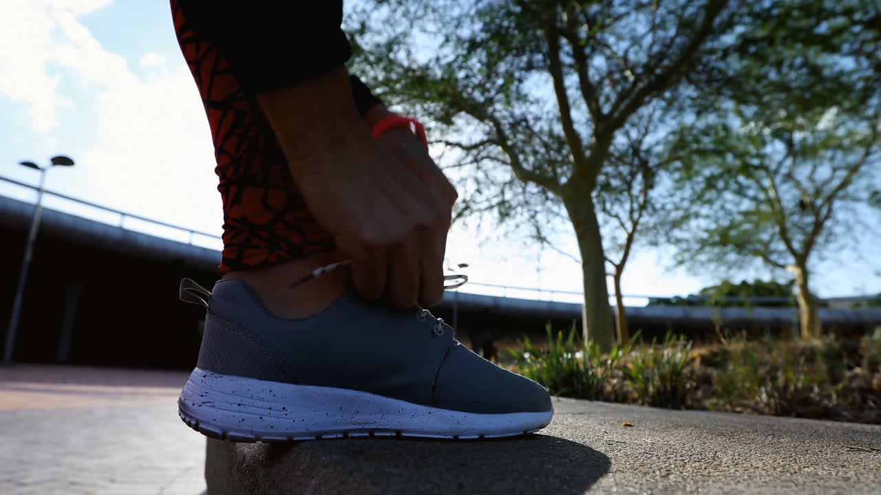 mujer atando los cordones de los zapatos mientras corre en el parque 4k