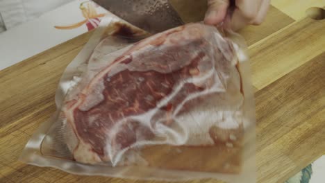el chef deja caer el filete de carne en un paquete al vacío en la tabla de cortar y lo abre