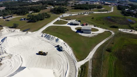 Video-Aéreo-De-Un-Cargador-De-Cangilones-Colocando-Material-Agregado-En-Un-Semirremolque-Para-Su-Transporte-Desde-Una-Mina-De-Arena-En-El-Centro-De-Florida