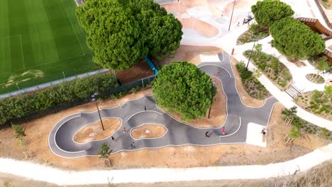 aerial view of kids scootering in skatepark amidst green trees