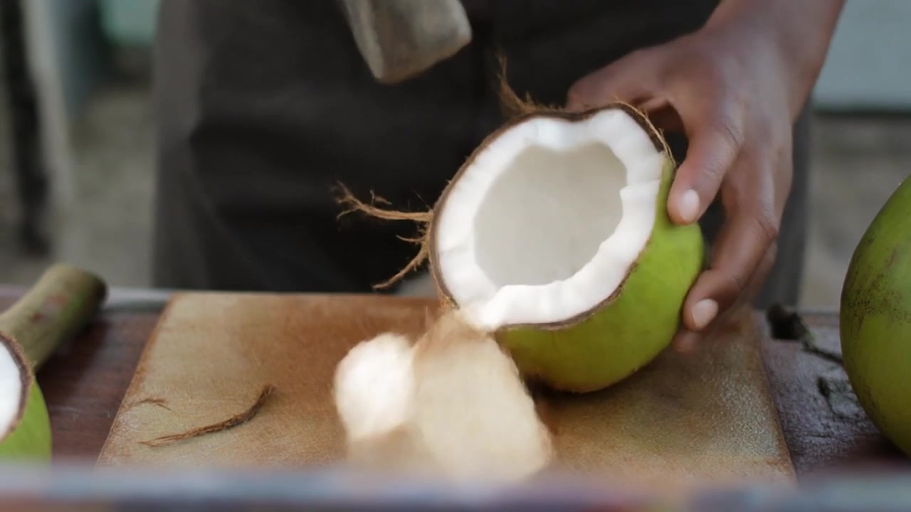 Person Using a Hammer to Open a Fresh Coconut