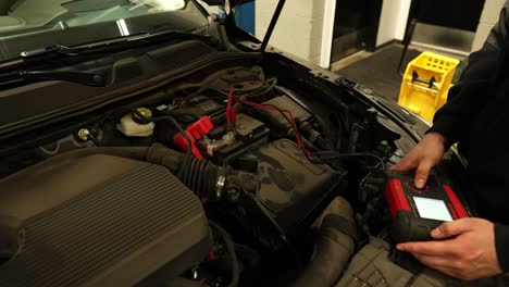 mechanic checking car battery, panning shot