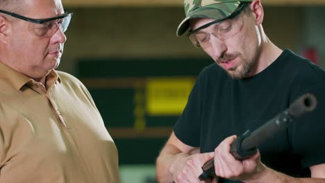 the trainee puts on protective glasses and earphones before taking a shot under the supervision of an instructor on a closed shooting range. a man learns how to shoot a shotgun