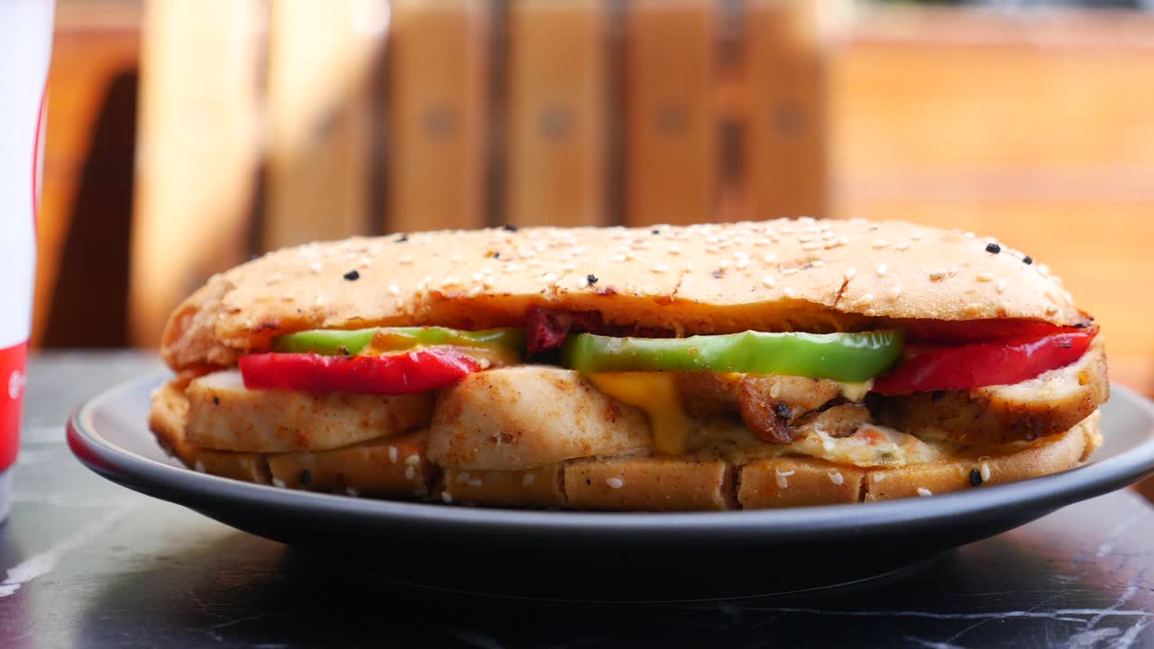 Primo piano di un panino con pollo grigliato, pomodoro e peperoni verdi