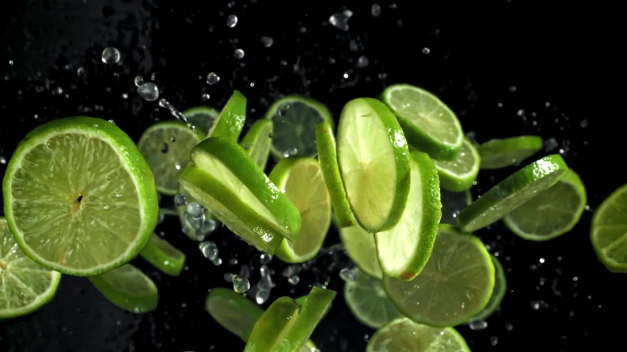 Fette di lime fresche in caduta con schizzi d'acqua in super slow motion