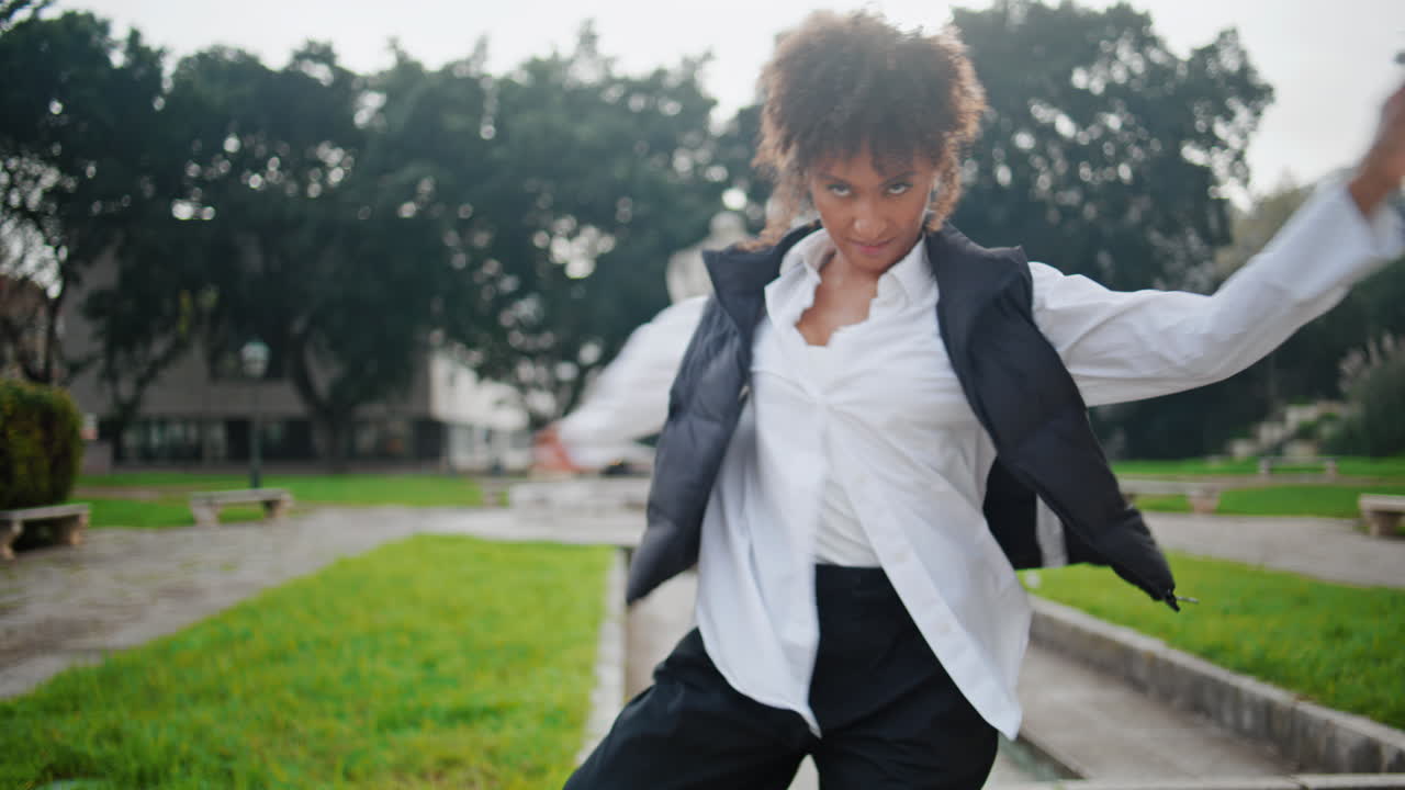 Trendy, energisk kvinne danser og har det gøy i byparken. Jente øver på dans