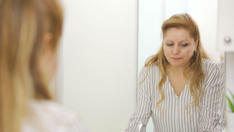 Mature-woman-motivates-herself-in-front-of-the-mirror-and-improves-her-morale.