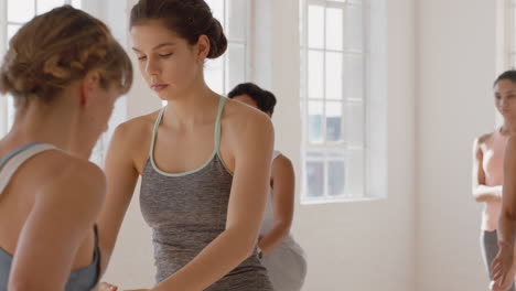 yoga class instructor teaching warrior pose to beautiful group of women enjoying healthy lifestyle exercising in fitness studio meditation