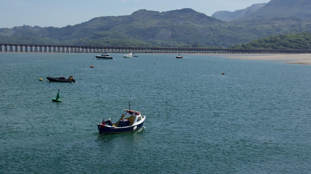 shot of the Barmouth rail bridge and Mawddach estuary looking east with small passenger ferry boat