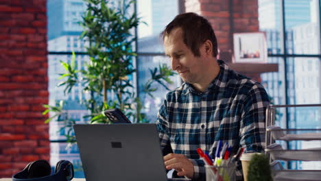 freelancer in home office at desk in front of laptop, answering phone call