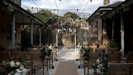 rustic floral wedding arch at the end of aisle- rows of wooden chairs
