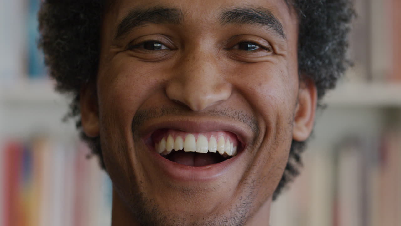 Ritratto di uomo afroamericano felice e sorridente davanti a una libreria