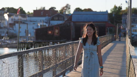 beautiful chinese girl’s smile, walks on wooden harbor bridge, at sunset