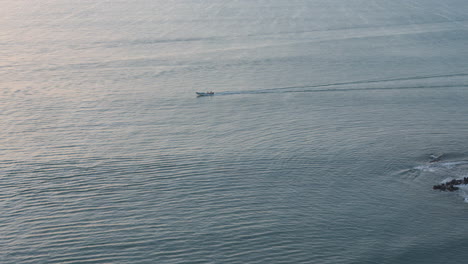 small boat cruising on calm waters near coronado at dusk, creating ripples, aerial view