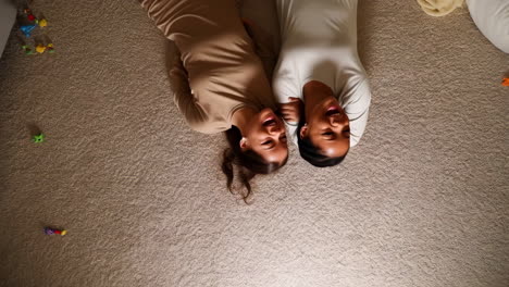 two sisters laying on the carpet