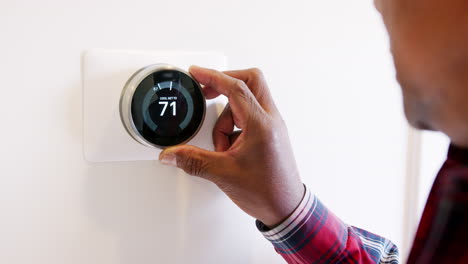 primer plano de un hombre configurando un termostato de calefacción inteligente en casa