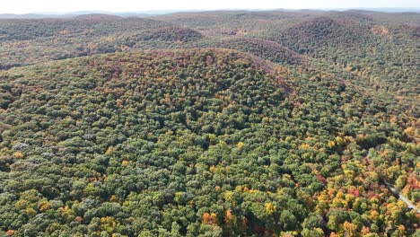 an aerial view high above the mountains in upstate ny during the fall foliage changes, on a bright and sunny day