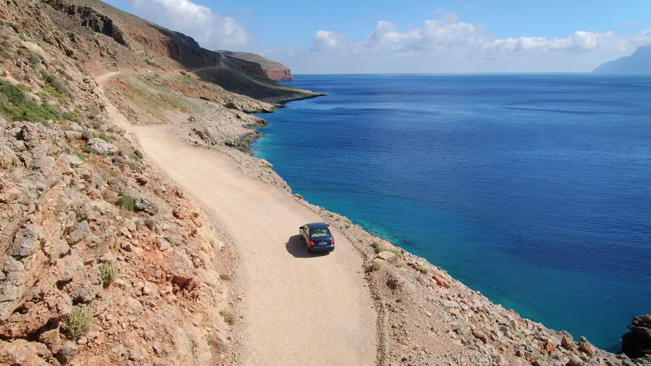 Aerial view of car driving on a mud road view of the rocky mountain range and seashore Kaliviani, Kissamos Province, Greece
