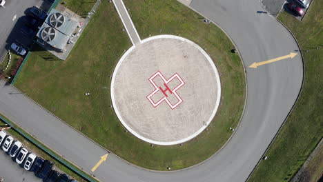 aerial overhead view of a helipad at a hospital, drone rising spin shot on a sunny day