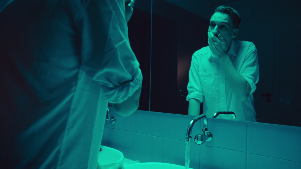 Man Washing Face in Neon Bathroom