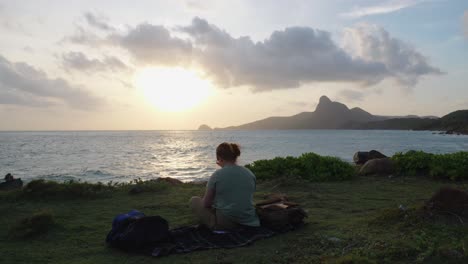 a woman sit and relaxing on the shore of a sunset beach in con dao island, vietnam