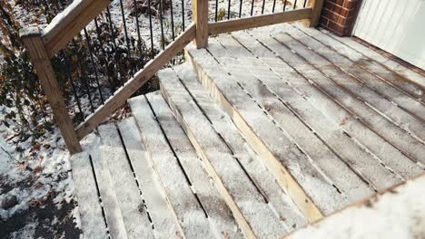 wooden steps in front of a home lightly covered in snow during winter